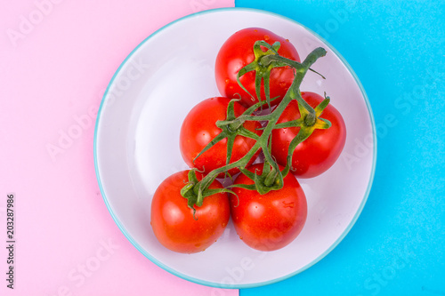 Branch of red tomatoes on bright background © ArtCookStudio