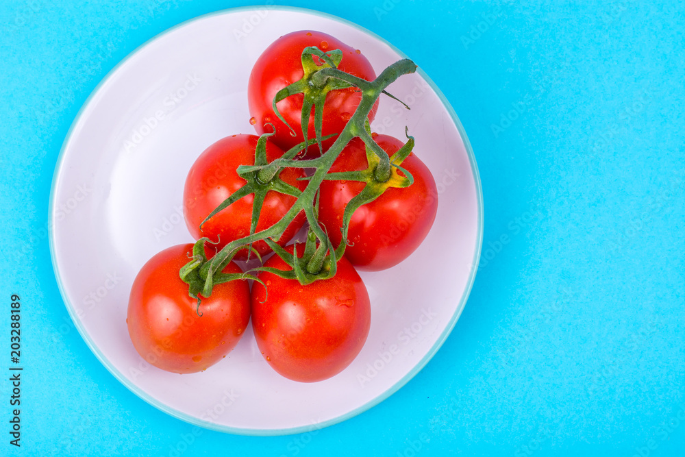 Branch of red tomatoes on bright background Branch of red tomatoes on bright background