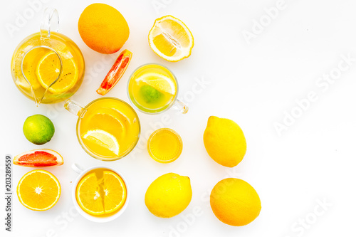 Fruit tea. Teacup and teapot among citrus on white background top view copy space