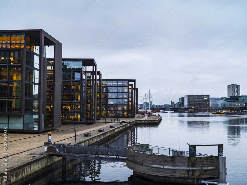 Modern buildings along side the Copenhagen harbor canal with blue sky and quiet waters Modern buildings along side the Copenhagen harbor canal with blue sky and quiet waters