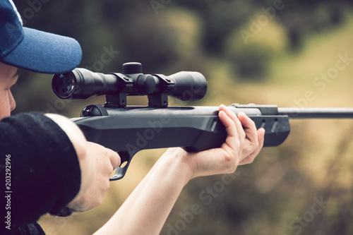 Young woman shooting rifle on farm