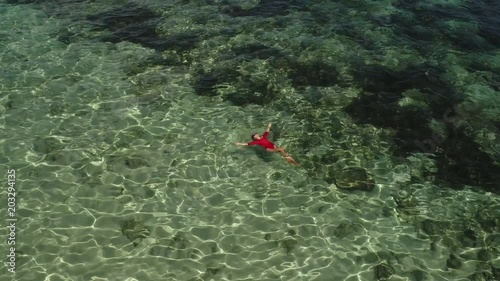 Summer image of beautiful girl swimming and lying on the back in the turquese sea water. Slim tanned body. Amazing sea landscape. Happy vacation. Sunbathing and relaxing photo