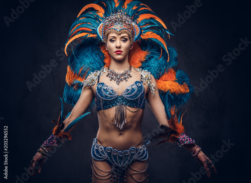 Studio portrait of a sexy female in a colorful sumptuous carnival feather suit. Isolated on a dark background.