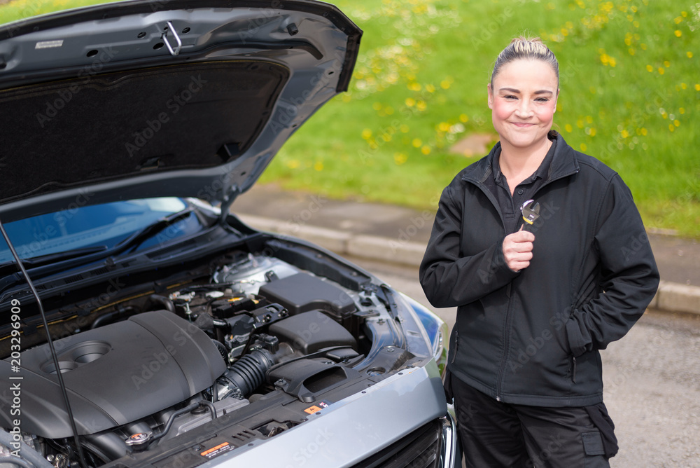 A woman mechanic repairing a car engine at roadside A woman mechanic repairing a car engine at roadside