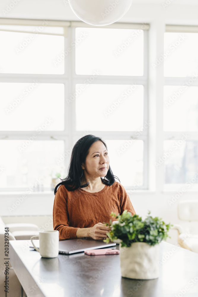 Businesswoman looking away against windows in office Businesswoman looking away against windows in office