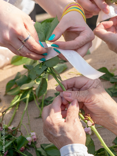 Female hands tie a ribbon on a bouquet of flowers.