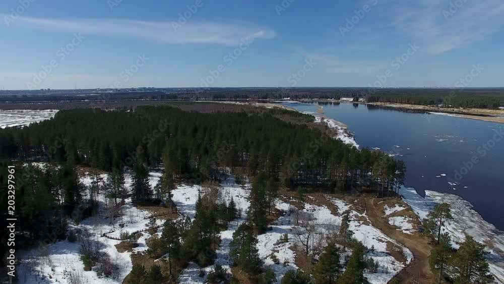 Forest And River In Spring Time. Video from the quadcopter over the forest and the river in the spring. The river is still floating ice. on the ground lies the snow