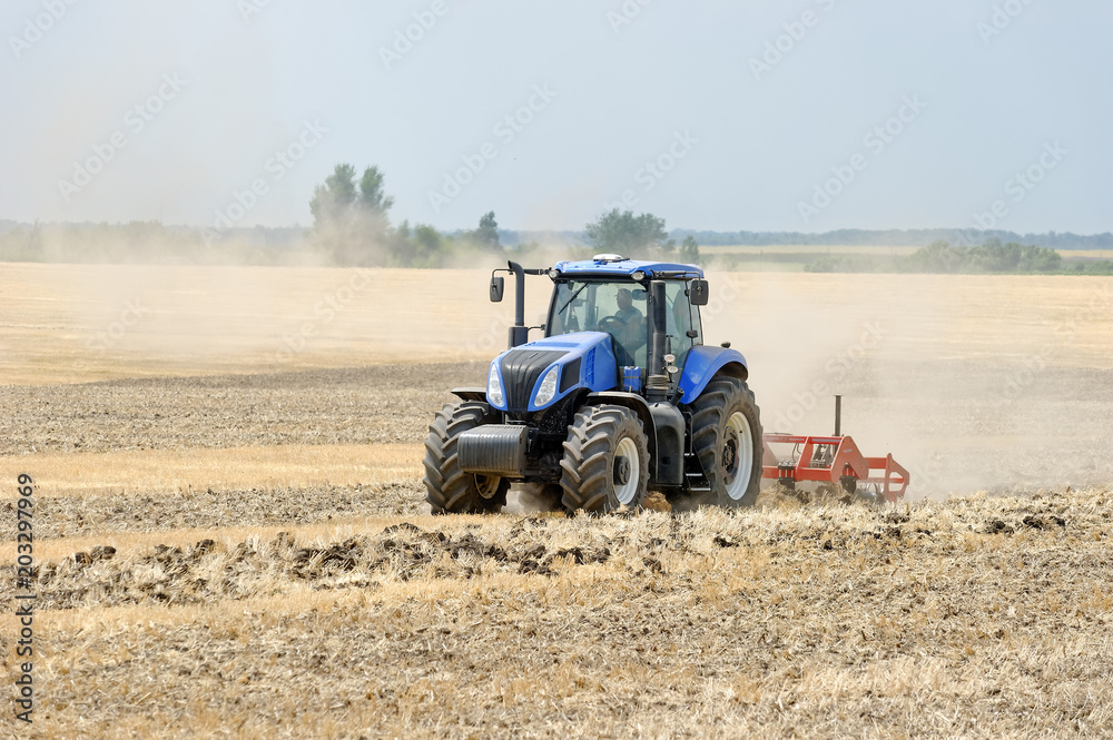 Tractor preparing land with plow, sunny summer day at agricultural field Tractor preparing land with plow, sunny summer day at agricultural field