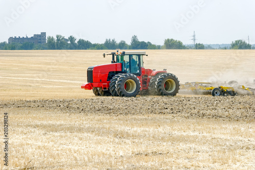 Tractor preparing land with plow  sunny summer day at agricultural field