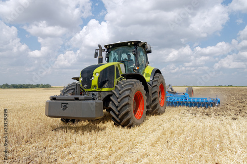 Tractor preparing land with plow  sunny summer day at agricultural field