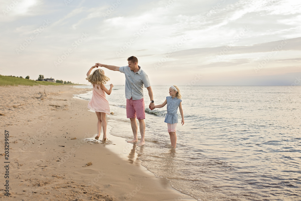Father playing with daughters on shore at beach Father playing with daughters on shore at beach
