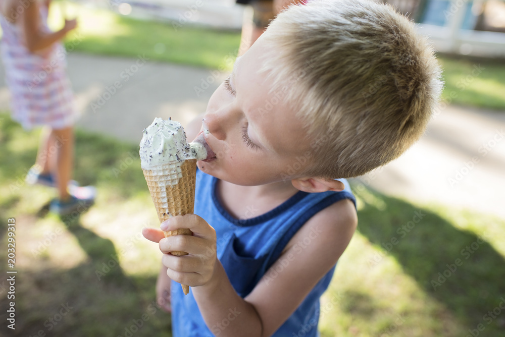 Boy licking melting ice cream while standing at backyard Boy licking melting ice cream while standing at backyard