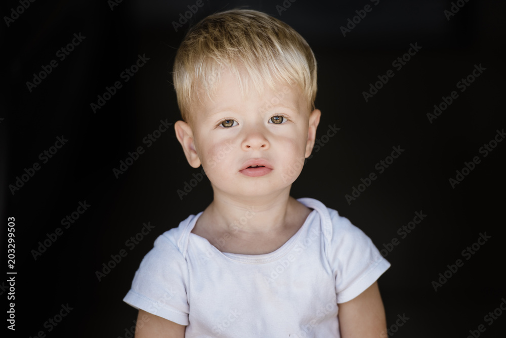 Portrait of boy standing against black background Portrait of boy standing against black background
