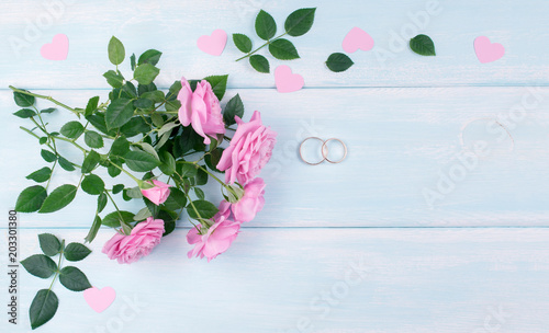 Top view of pink roses and bridal rings for wedding on background of shabby wooden planks