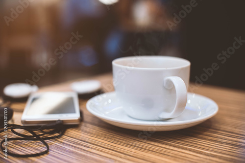 Cup of hot coffee and smartphone in cafe.Selective focus