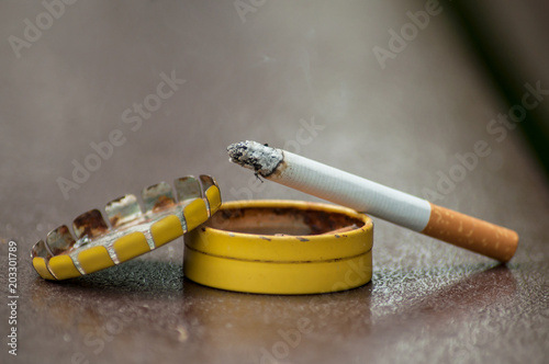 closeup of cigarette on metallic pocket ashtray on wooden table background