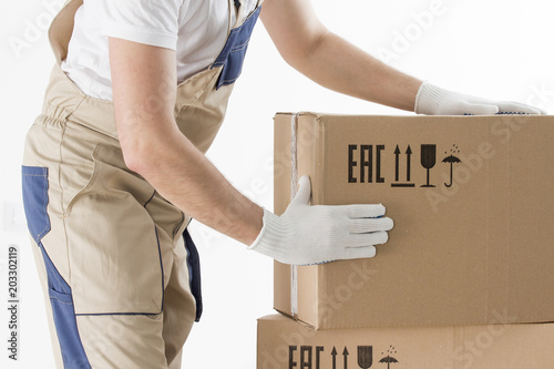 Obraz na płótnie relocation services concept. Mover's hands In uniform carrying cardboard Box. Loader puts cardboard boxes isolated on white background. Worker mover unloading paper box. Delivery man w salonie