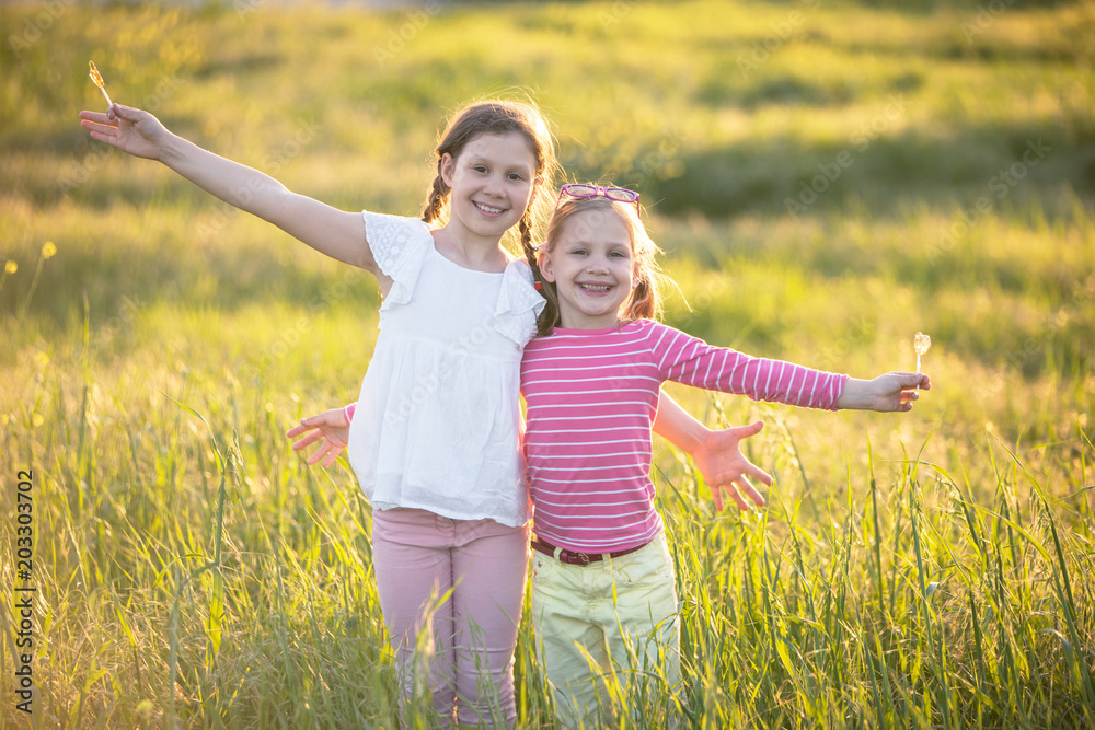 ..portrait of two little girls standing in green grass at sunset ..portrait of two little girls standing in green grass at sunset