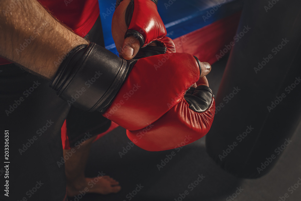 A fighter puts on gloves before a fight. Fighter training on the punching bag. Mixed fight close up. 