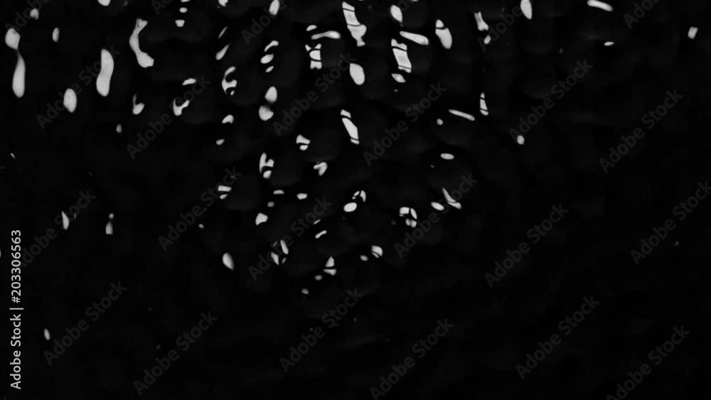 Dancing circles on the water surface forming due to vibration. Black background. Slow motion