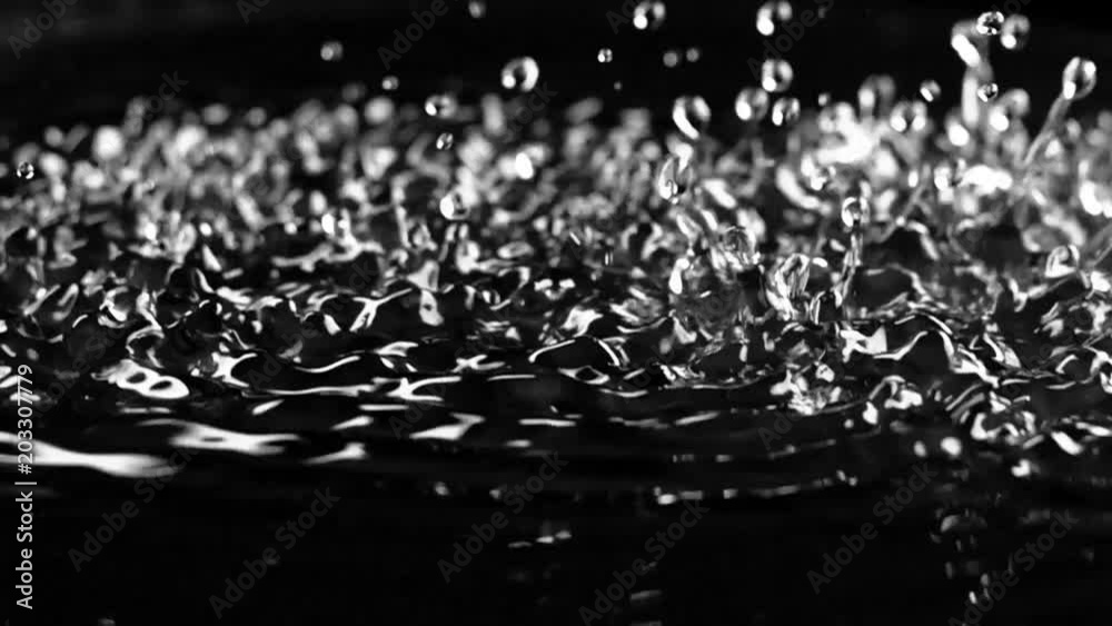 Excitement of the water surface by ultrasonic frequencies. Black background. Slow motion