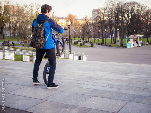 young man walking in the urban street of the city with bmx