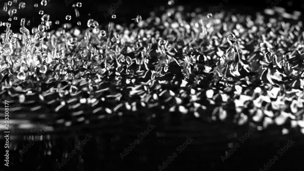 Strong vibration lifts the water drops up. Black background. Slow motion