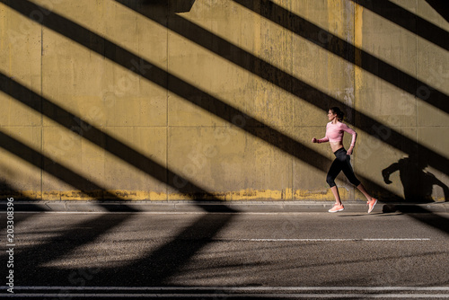 Young fit blonde woman running in the street