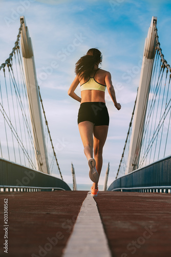 Young fit blonde woman running on the bridge