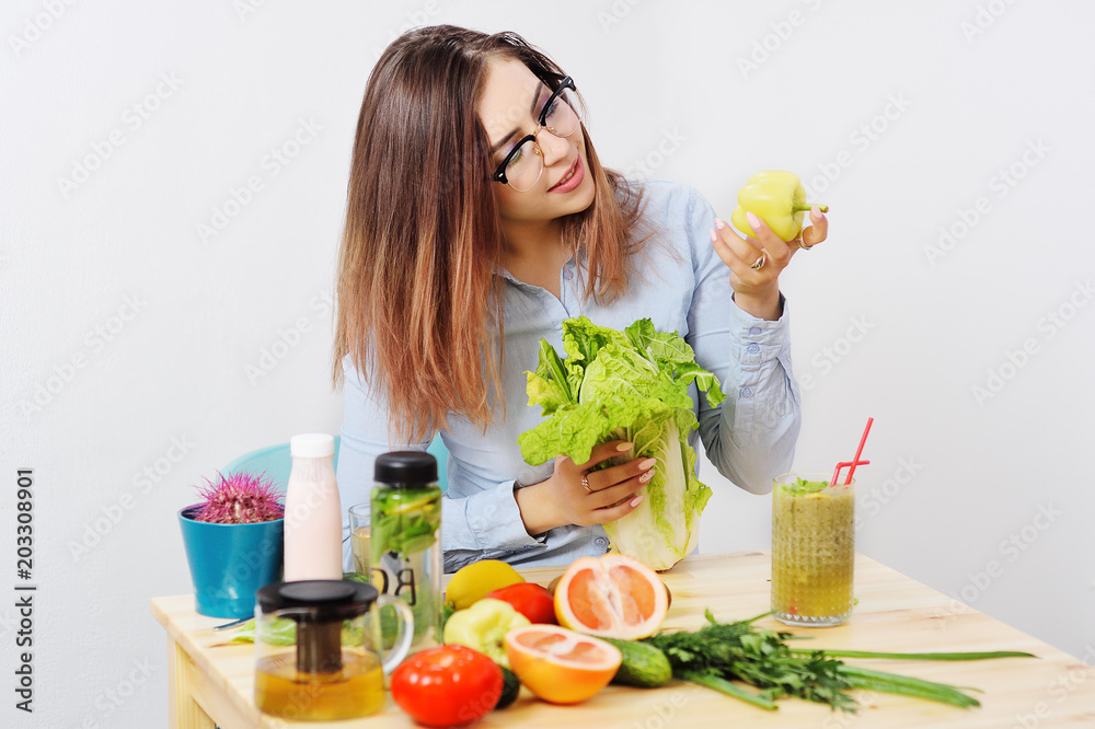 beautiful young girl with glasses with Peking cabbage and pepper in hands on the background of a table with vegetables. Healthy Eating, Weight Loss, Diet, Vegetarianism, Nutrition, Lifestyle beautiful young girl with glasses with Peking cabbage and pepper in hands on the background of a table with vegetables. Healthy Eating, Weight Loss, Diet, Vegetarianism, Nutrition, Lifestyle