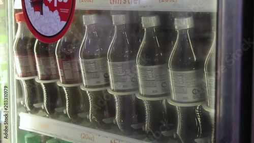 Grabbing a soda bottle from a refrigerated case at a convenience store