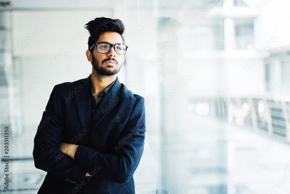 Happy indian business man in suit standing in modern office