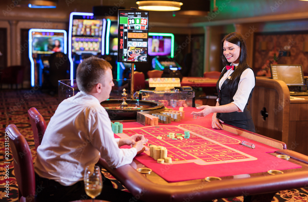 Cute lady casino dealer at Roulette table. Happy gentleman is playing  Roulette. Stock Photo | Adobe Stock