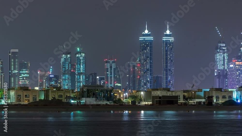 Modern Dubai city skyline timelapse at night with illuminated skyscrapers over water surface photo