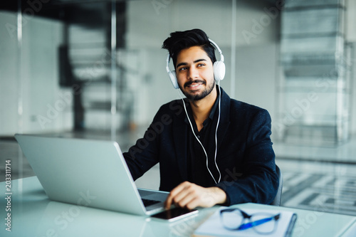 Young businessman working with laptop computer and headphone in the office