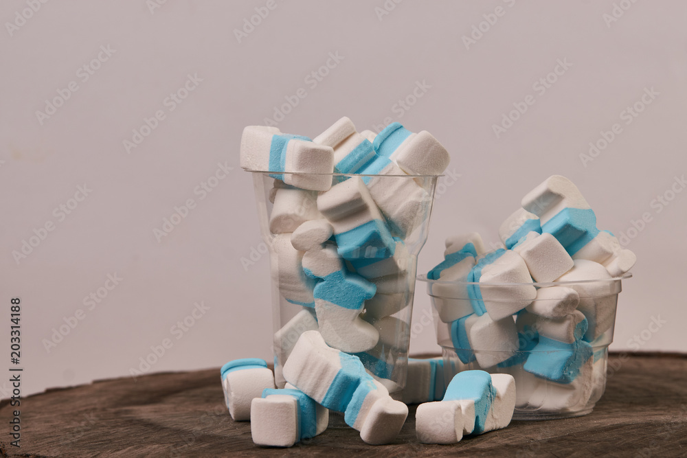 Marshmallow in a plastic glass on wooden table background, close-up. Sweet unhealthy snack Marshmallow in a plastic glass on wooden table background, close-up. Sweet unhealthy snack