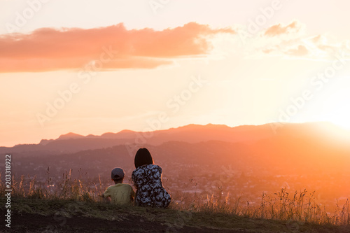 Mom and son enjoy together their sunset over the mountain and the town.