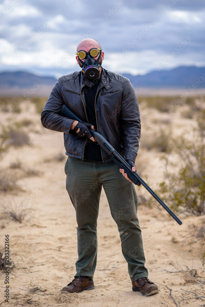 In a post-apocalyptic desert wasteland, a male model armed with axes is ...