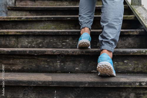 Women feet walking up stairs old wood.