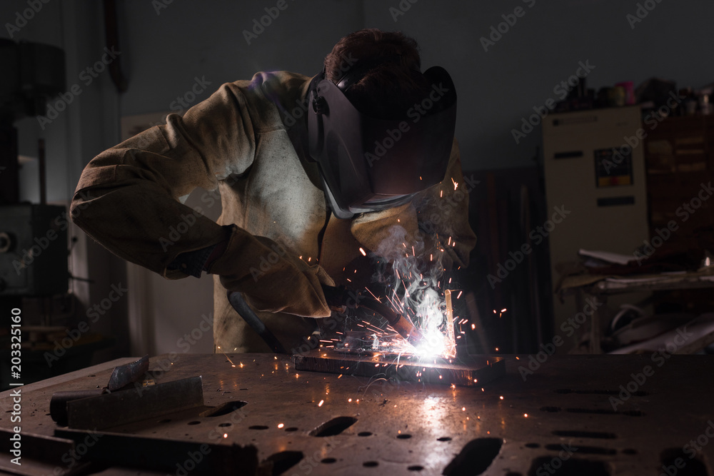 worker in protection mask welding metal at factory worker in protection mask welding metal at factory