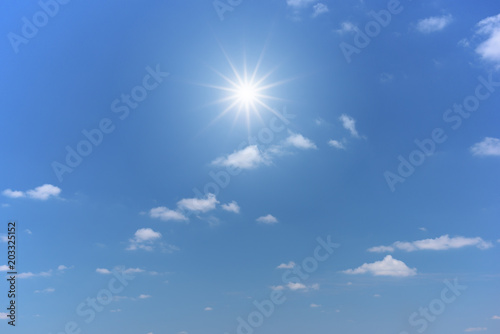 Sun on blue sky with white clouds.