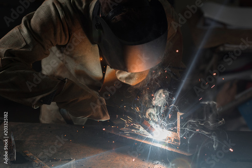 manufacture worker welding metal with sparks at factory