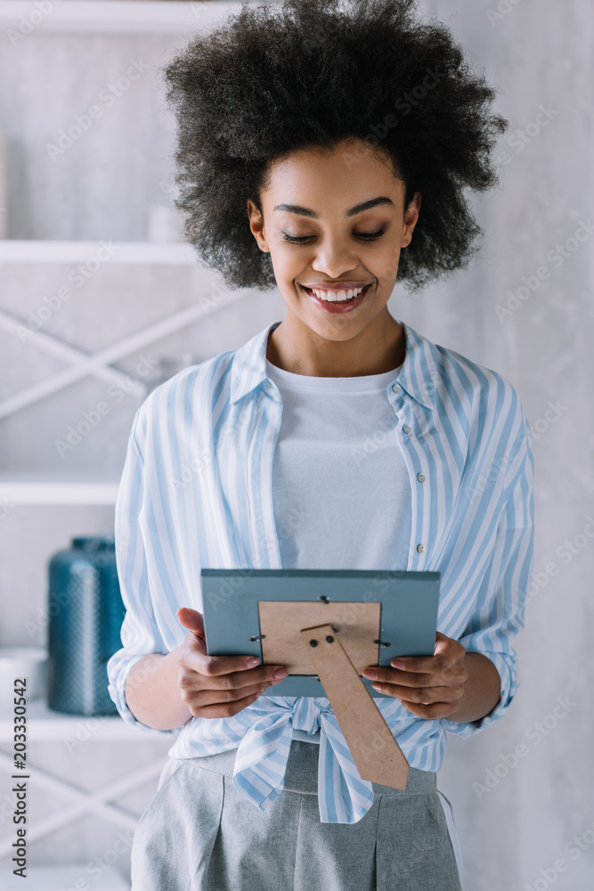 Happy african american woman looking at photo frame Happy african american woman looking at photo frame