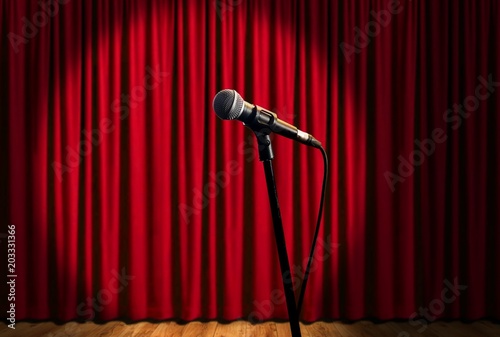 microphone on stage under spotlights with red curtain