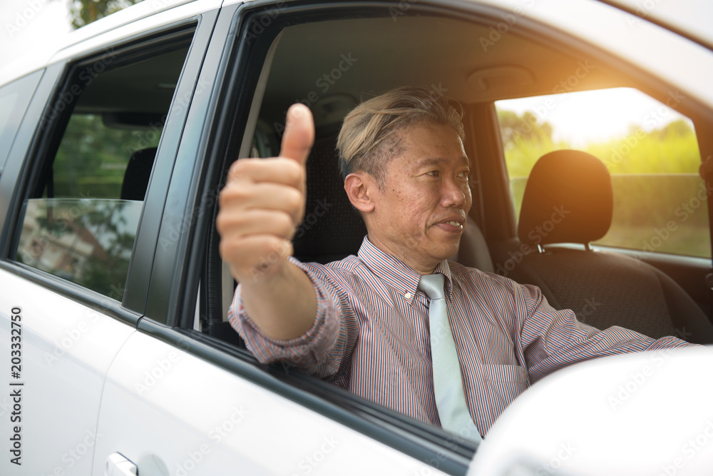 asian senior male driving with thumbs up