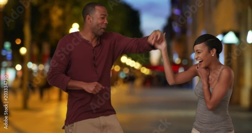 Playful African-American couple dancing together on the Champs-Elysees, Youthful black boyfriend and girlfriend embrace after a short dance together on a romantic night out in Paris, 4k