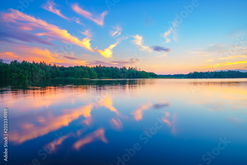 Beautiful landscape with colorful sunset over forest lake © sborisov