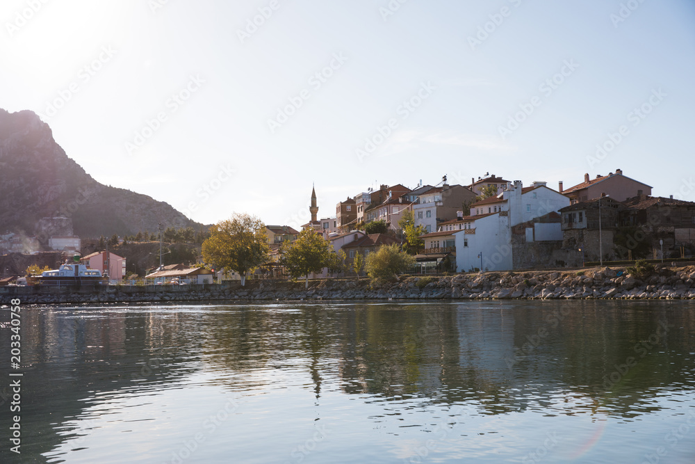 traditional buildings reflected in calm water, mountains and coast, lake egirdir, turkey