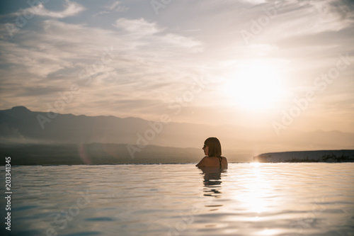 young woman relaxing in beautiful pool at sunset, pamukkale, turkey