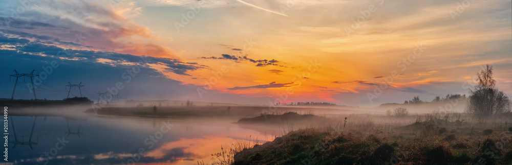 Panoramic view of the sunrise over the lake, beautiful landscape with morning fog, breathtaking summer sunrise. The beauty of nature concept background